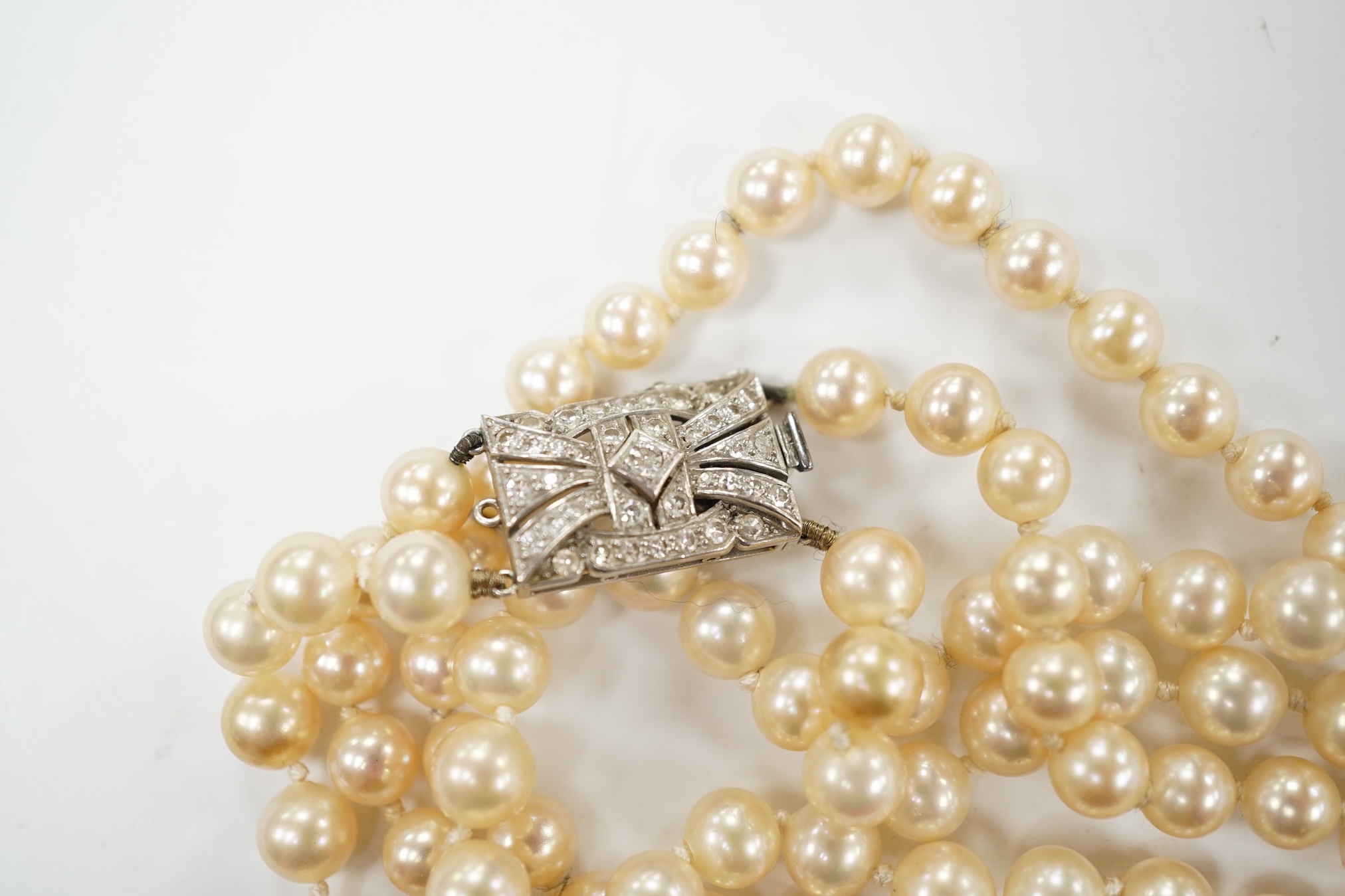 A double strand simulated pearl necklace, with diamond cluster set white metal clasp, 90cm. Condition - fair